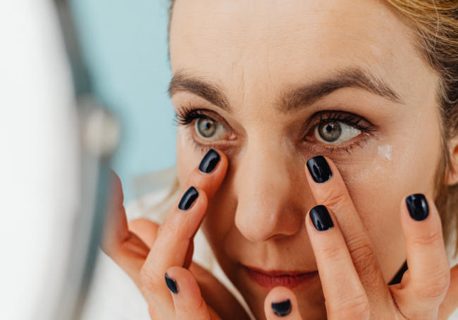 Woman using eye cream on under eye bags and dark circles.