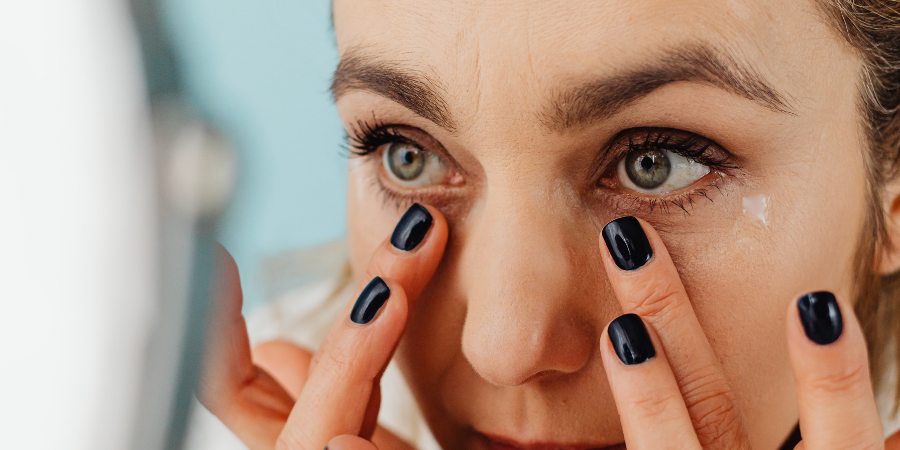 Woman using eye cream on under eye bags and dark circles.
